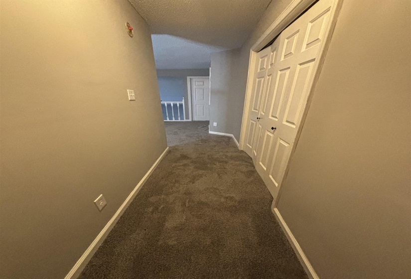 Corridor with a textured ceiling and dark carpet