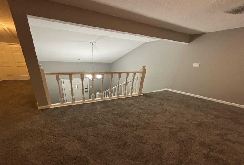 Spare room featuring dark carpet and baseboards