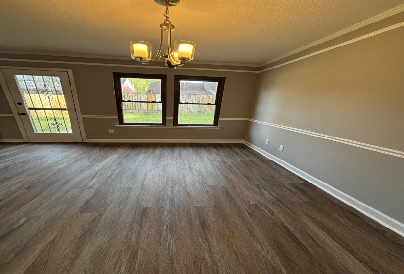 Unfurnished dining area with suspended lighting, crown molding, a textured ceiling, and dark wood-style flooring