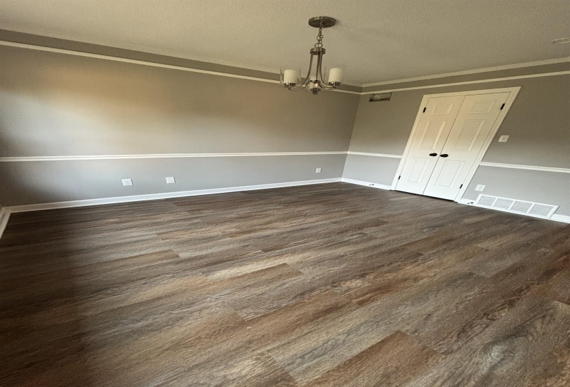 Unfurnished dining area featuring a chandelier, dark wood-style flooring, ornamental molding, and a textured ceiling