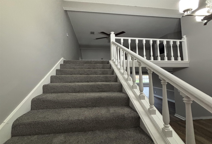 Staircase with a ceiling fan and baseboards
