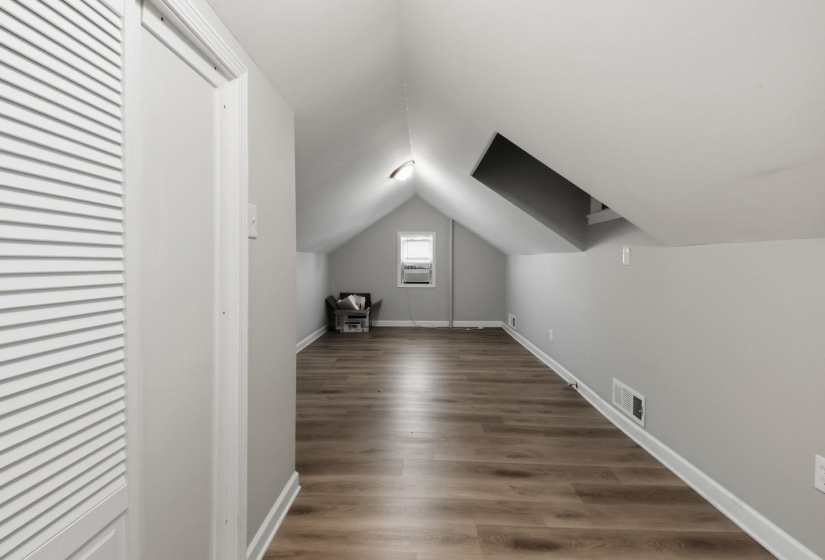 Bonus room with vaulted ceiling, dark wood-type flooring, and cooling unit