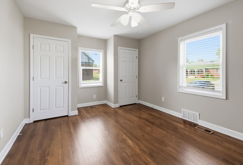 Unfurnished bedroom featuring multiple closets, dark wood finished floors, and a ceiling fan