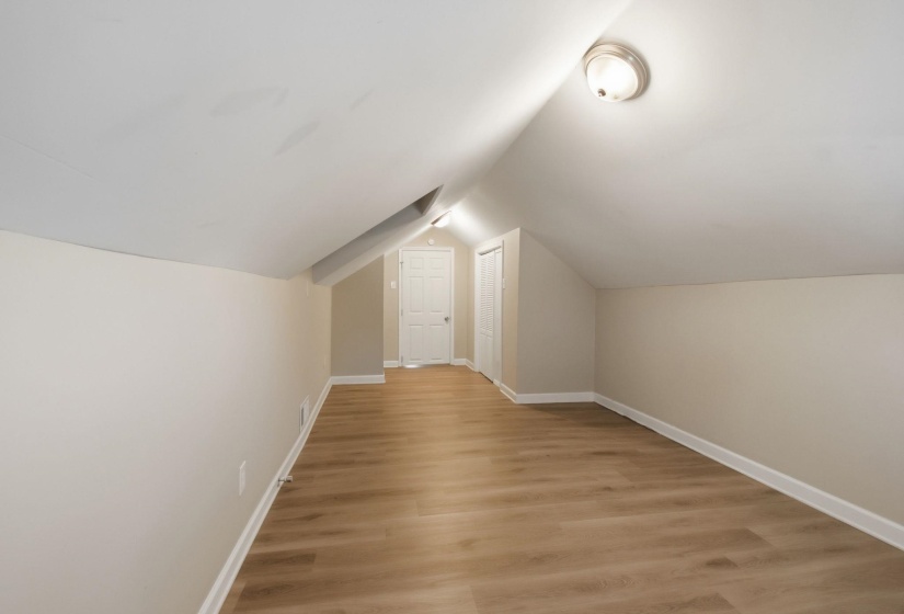 Bonus room featuring light wood-style flooring and vaulted ceiling