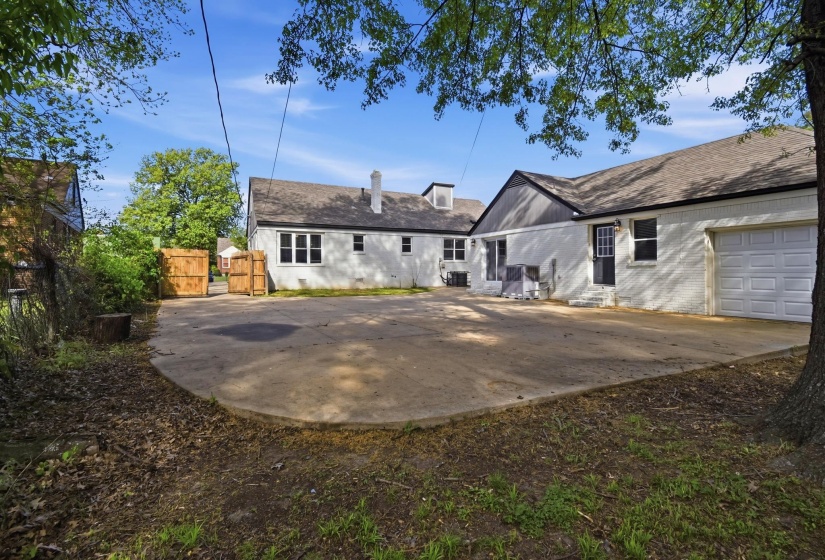 Back of house with a patio area, an attached garage, brick siding, a gate, and a shingled roof