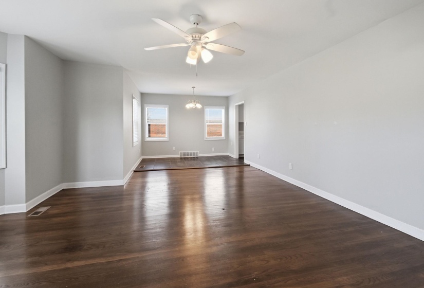 Unfurnished room with ceiling fan, dark wood-style flooring, and a chandelier