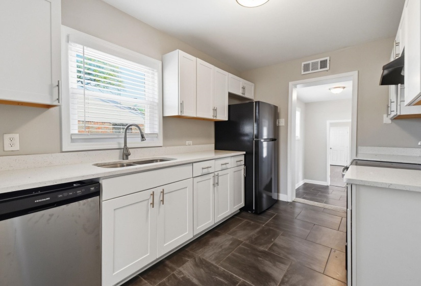 Kitchen featuring dishwasher, white cabinets, light stone countertops, freestanding refrigerator, and electric stove