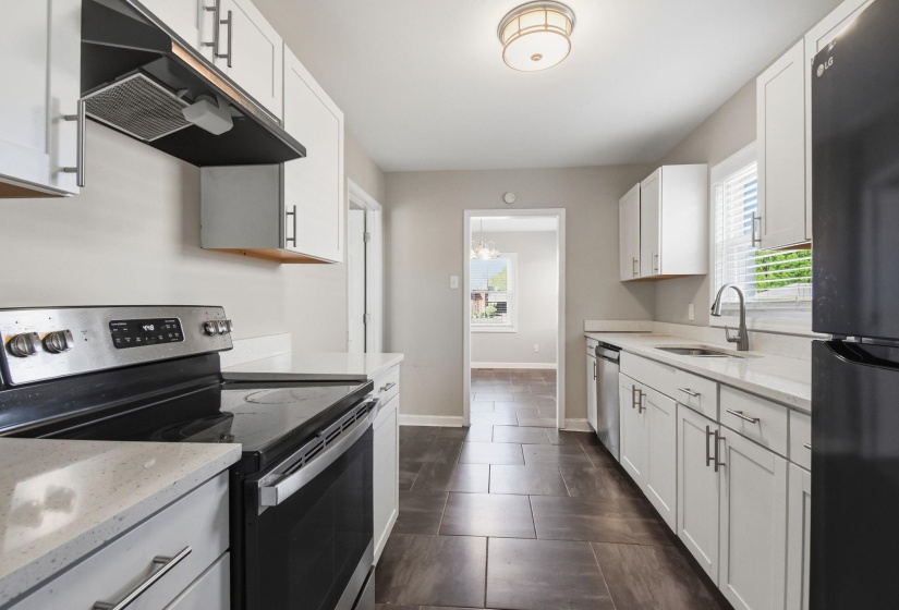 Kitchen featuring stainless steel appliances, ventilation hood, white cabinets, light stone counters, and plenty of natural light