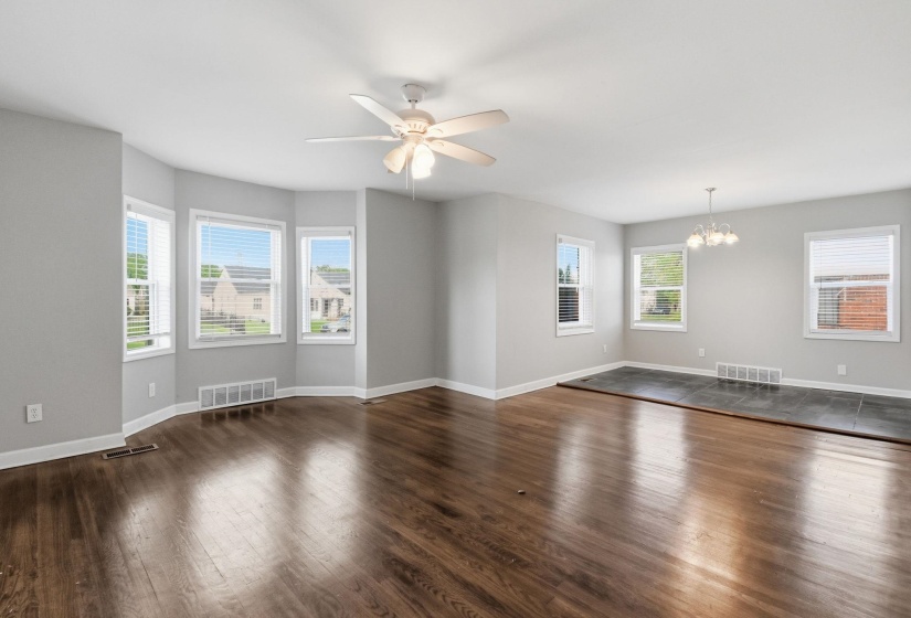 Empty room featuring ceiling fan, a chandelier, and dark wood-style flooring