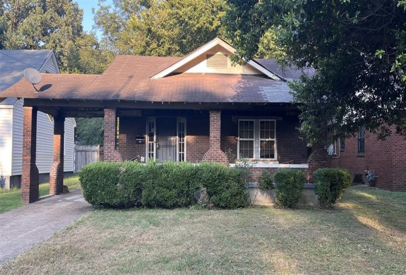 View of front of property with a front lawn, a shingled roof, brick siding, and covered porch