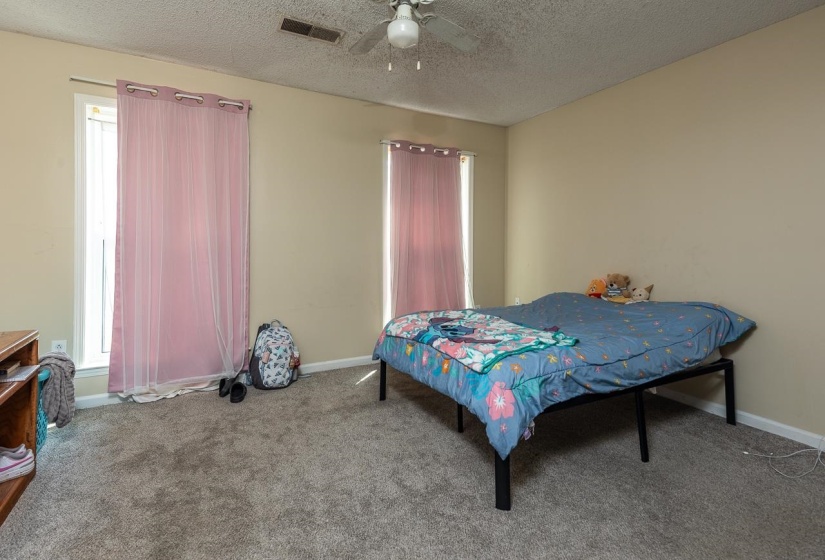 Carpeted bedroom with a textured ceiling and ceiling fan