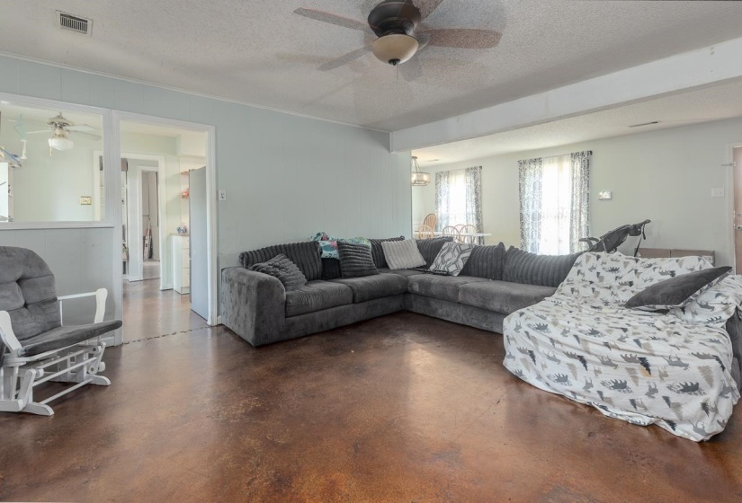 Living area with ceiling fan, a textured ceiling, concrete floors, and crown molding