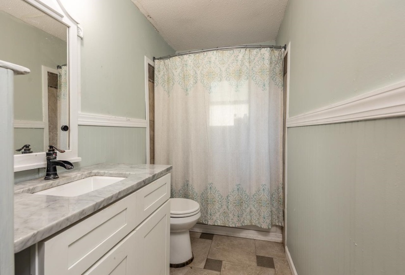 Full bathroom with a textured ceiling and vanity