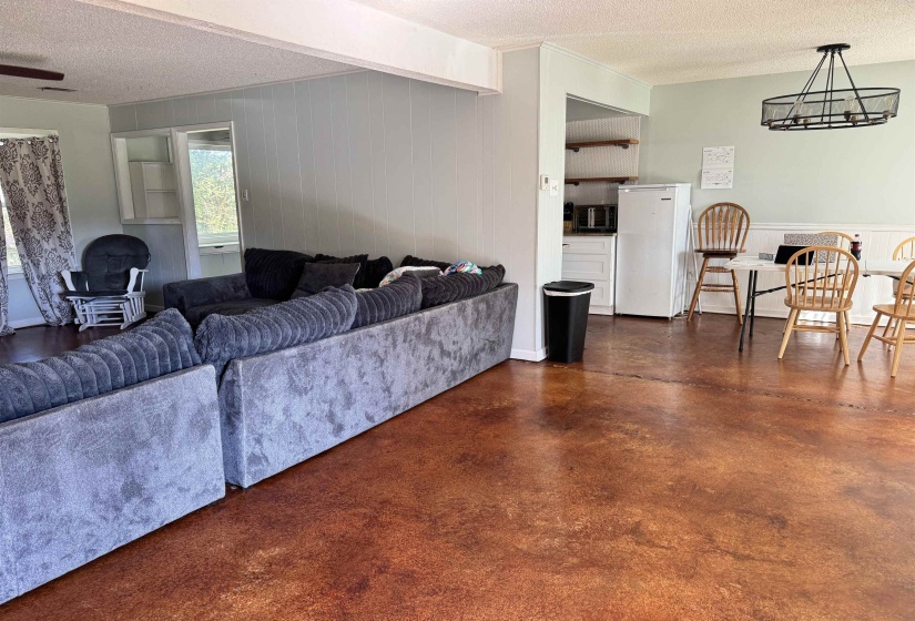 Living room with wood walls, concrete floors, a textured ceiling, and a chandelier