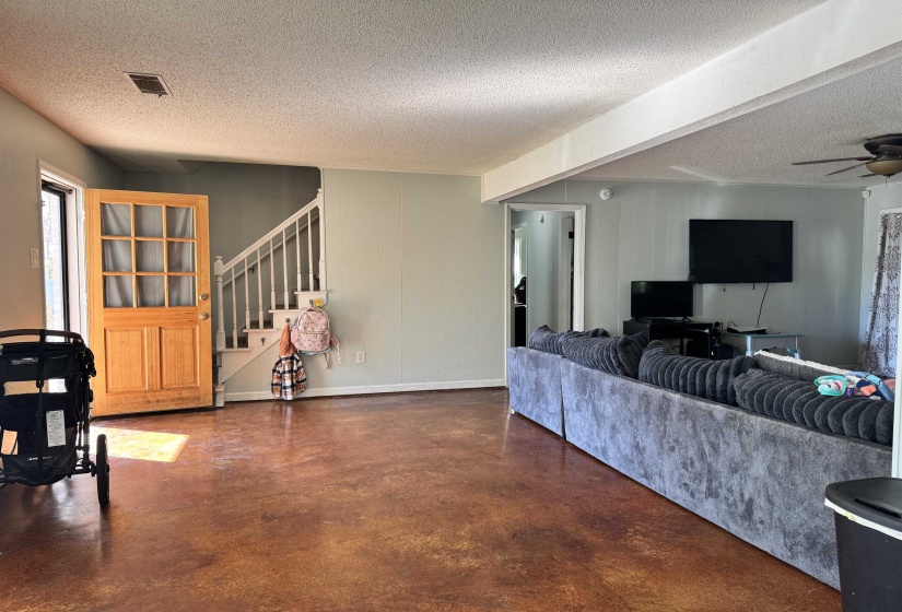 Living area featuring concrete flooring, a textured ceiling, stairway, and a ceiling fan