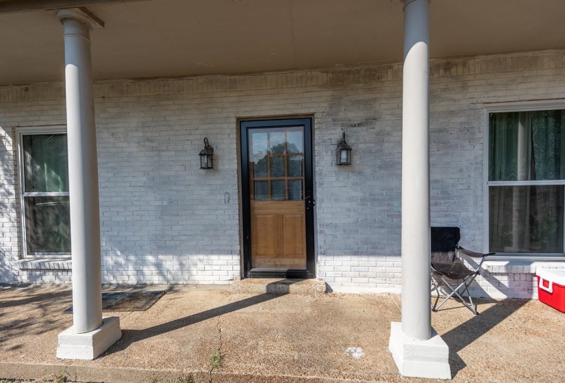 View of exterior entry with covered porch and brick siding