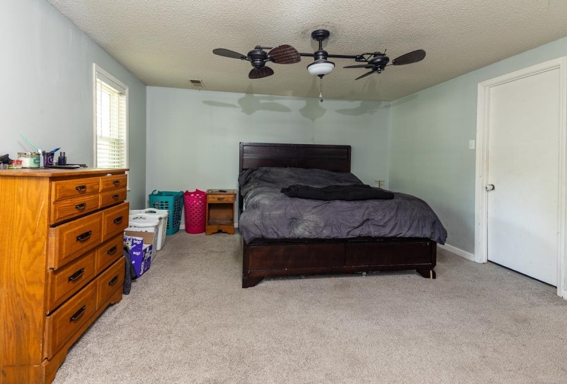 Bedroom featuring a textured ceiling, light carpet, and a ceiling fan