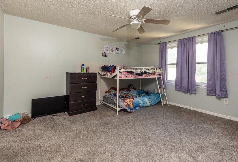 Bedroom with a textured ceiling, carpet flooring, and ceiling fan