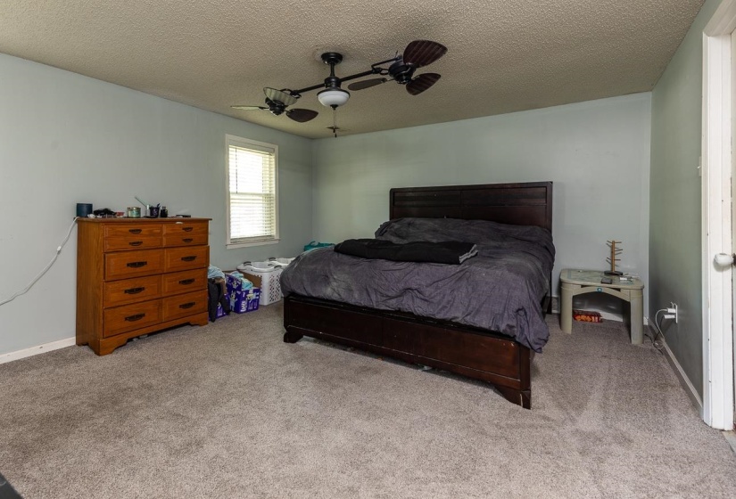 Carpeted bedroom with a textured ceiling and ceiling fan