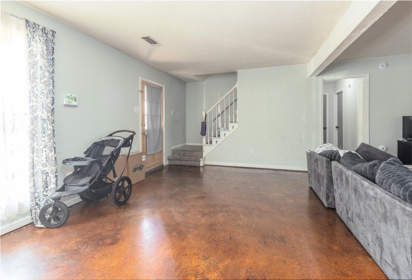 Living area featuring concrete floors, stairway, and a textured ceiling