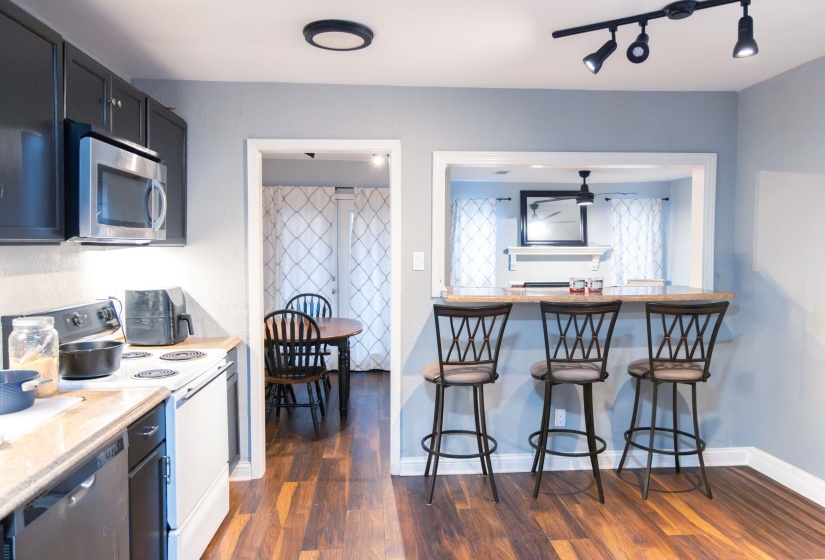 Kitchen with appliances with stainless steel finishes, a breakfast bar, dark wood finished floors, and light stone counters