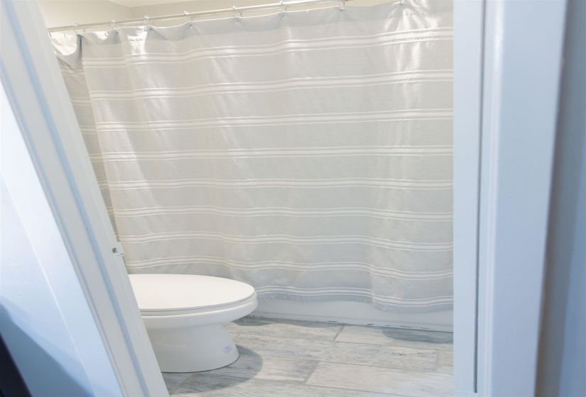 Full bathroom with toilet and light wood finished floors