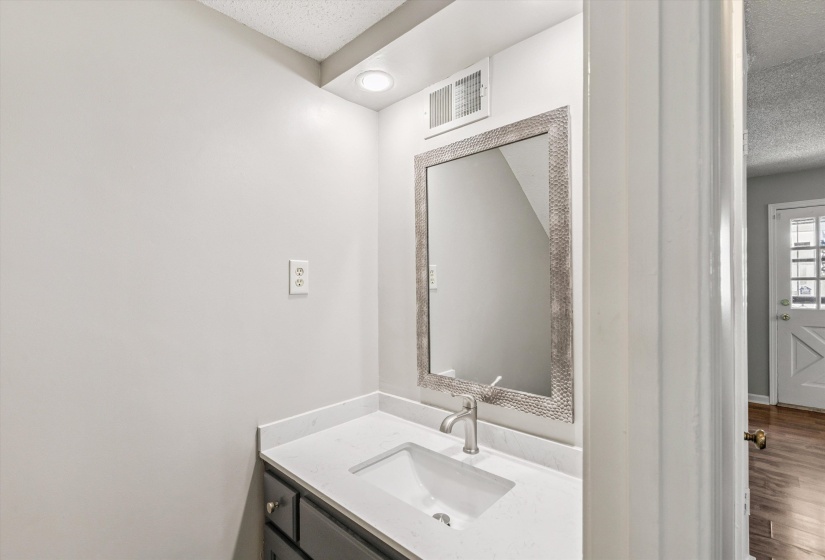 Bathroom featuring a textured ceiling, vanity, and wood finished floors