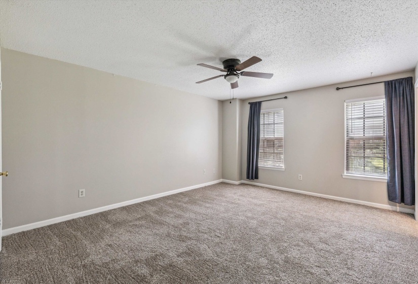 Carpeted empty room with ceiling fan and a textured ceiling