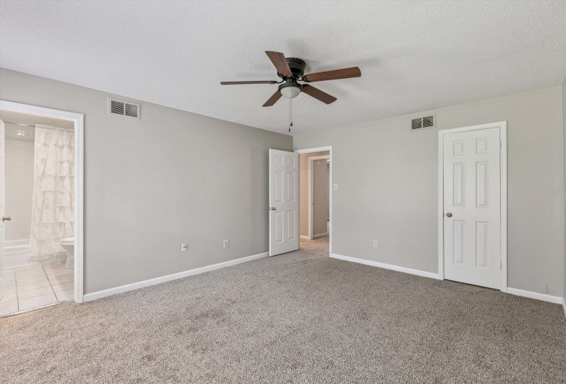 Unfurnished bedroom with a textured ceiling, carpet floors, connected bathroom, and ceiling fan