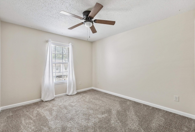 Carpeted empty room with a textured ceiling and a ceiling fan