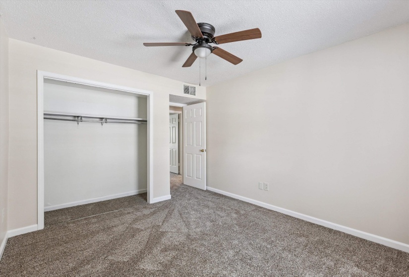 Unfurnished bedroom with a textured ceiling, carpet floors, a closet, and ceiling fan