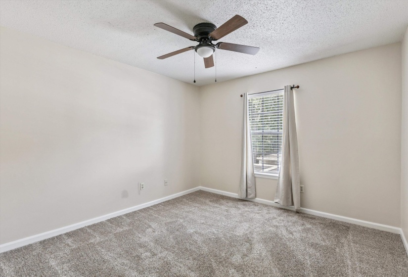Carpeted empty room with a textured ceiling and a ceiling fan