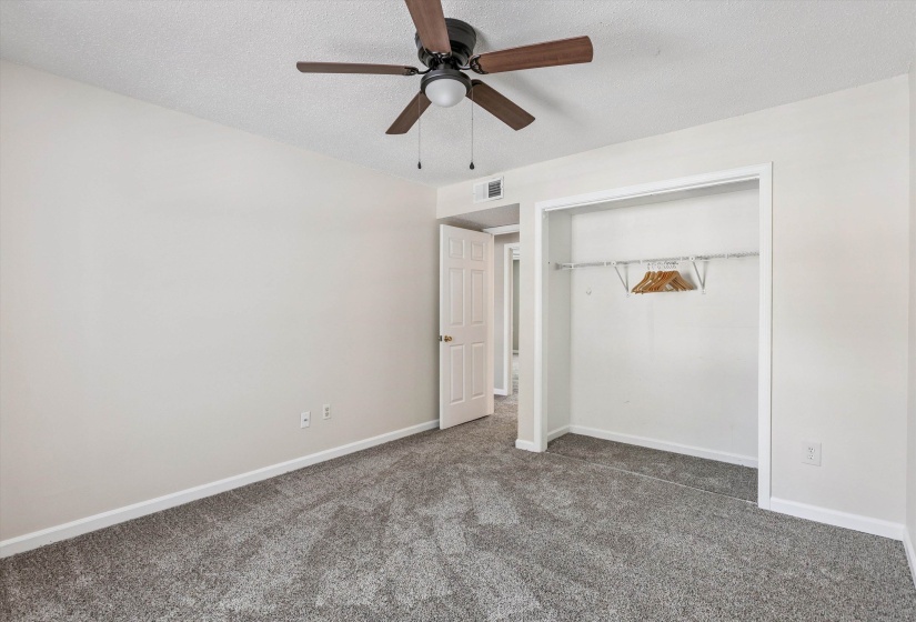 Unfurnished bedroom featuring a textured ceiling, carpet, a closet, and ceiling fan
