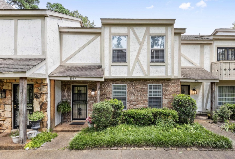 Tudor house featuring stucco siding, brick siding, and a shingled roof