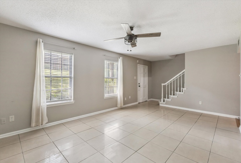 Foyer with a ceiling fan, a textured ceiling, stairway, and light tile patterned floors
