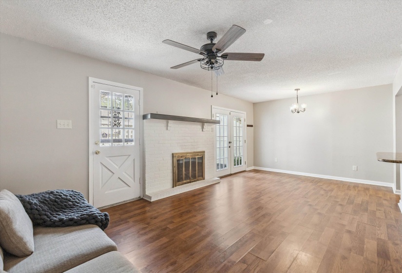 Living area featuring a textured ceiling, wood finished floors, a chandelier, ceiling fan, and plenty of natural light
