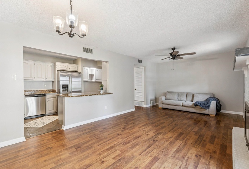 Unfurnished living room with ceiling fan, a textured ceiling, wood finished floors, and a chandelier