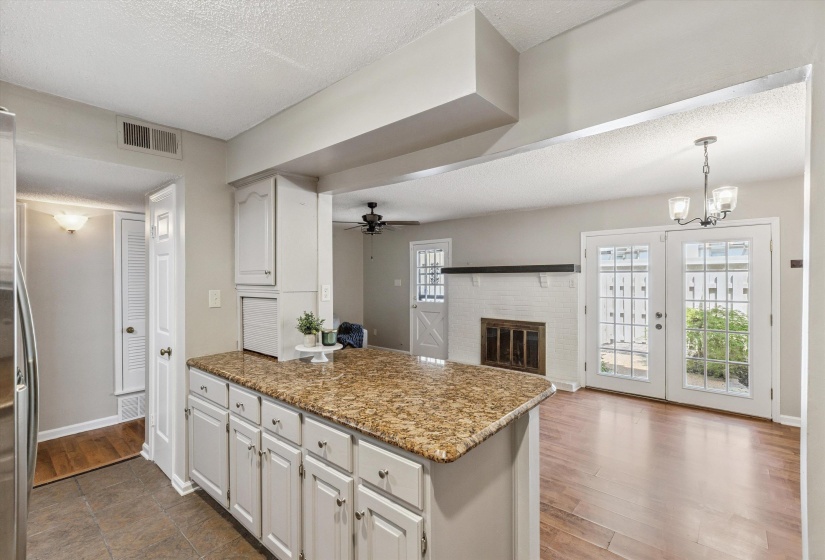 Kitchen featuring a textured ceiling, a peninsula, ceiling fan, wood finished floors, and white cabinetry