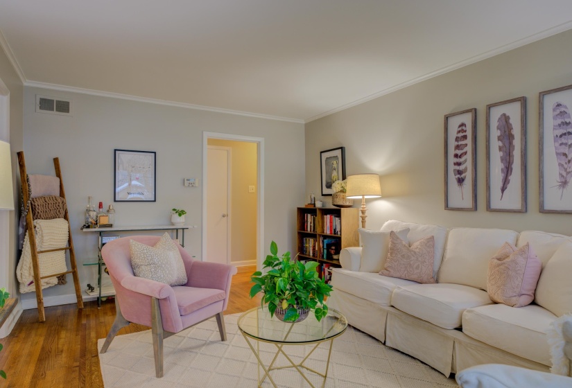Living room featuring wood-finish flooring, light-colored wall paint, and white crown molding