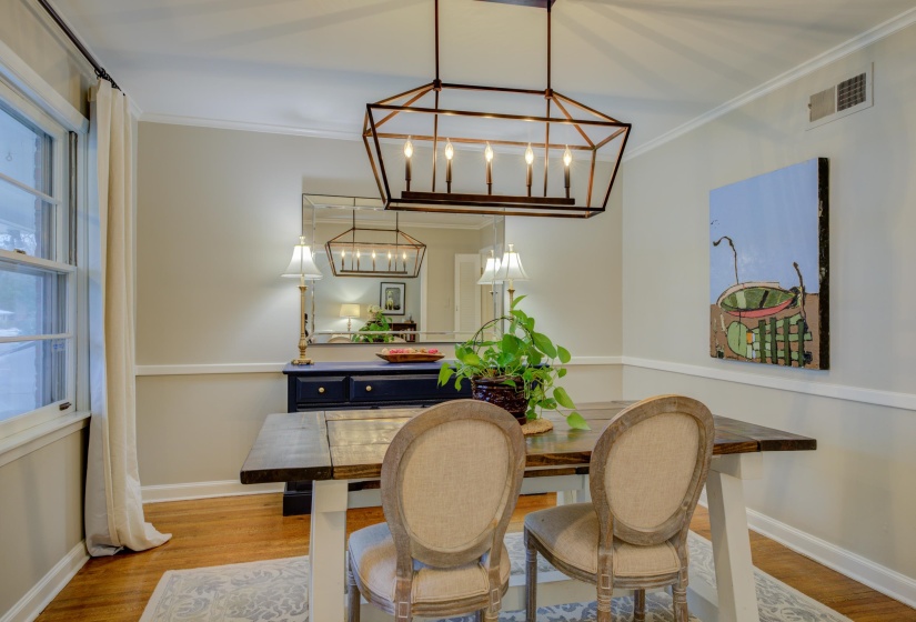 Dining space featuring a linear geometric chandelier, wood-finish flooring, and crown molding