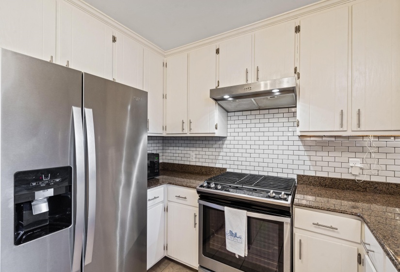 Kitchen featuring stainless steel appliances, white cabinetry, a subway tile backsplash, and stone countertops