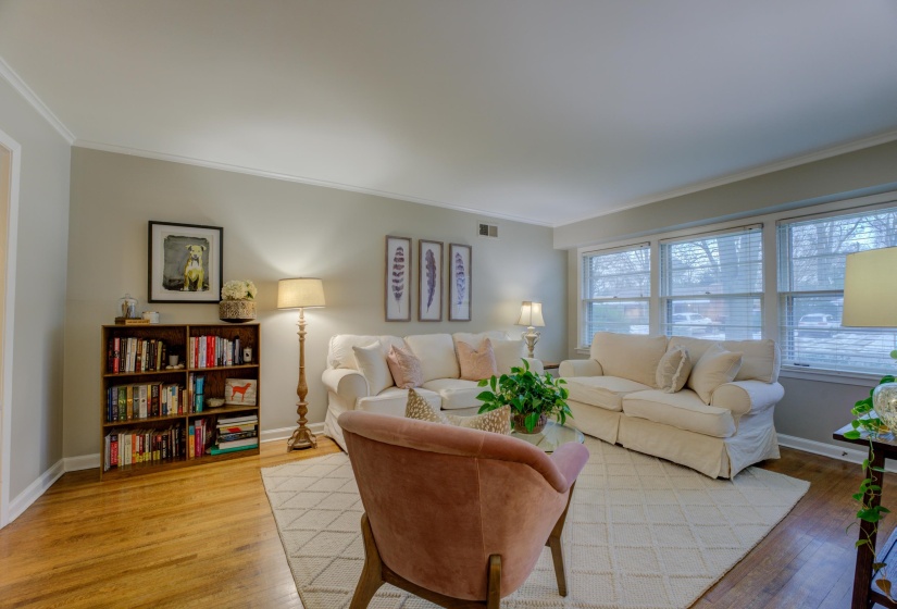 Living space featuring wood-finish flooring, light gray wall paint, and white crown molding