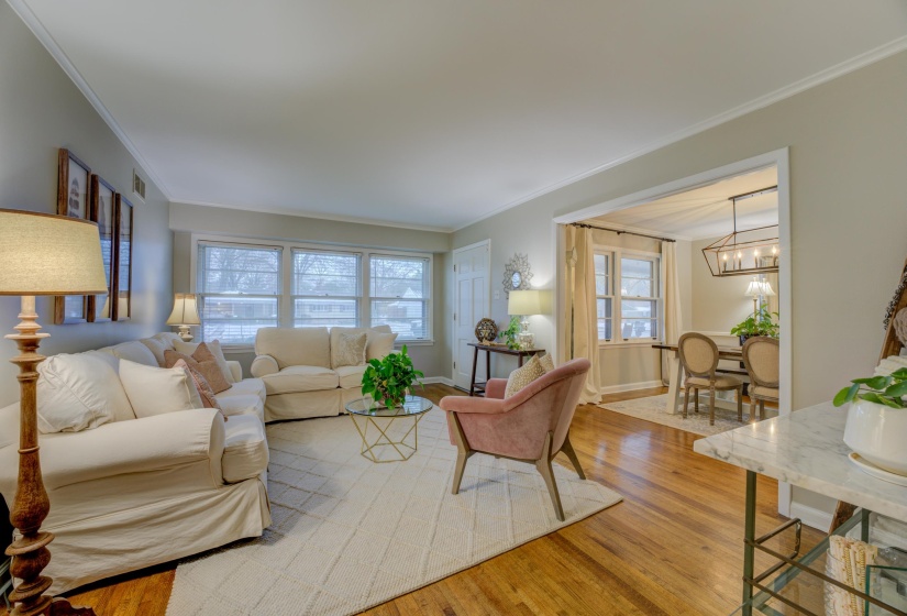 Spacious living area featuring rich hardwood flooring, crown molding, and multiple windows