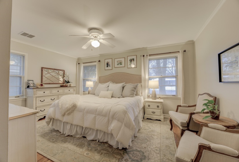 Spacious room featuring multiple windows, crown molding, a ceiling fan with integrated lighting, and wood-finish flooring