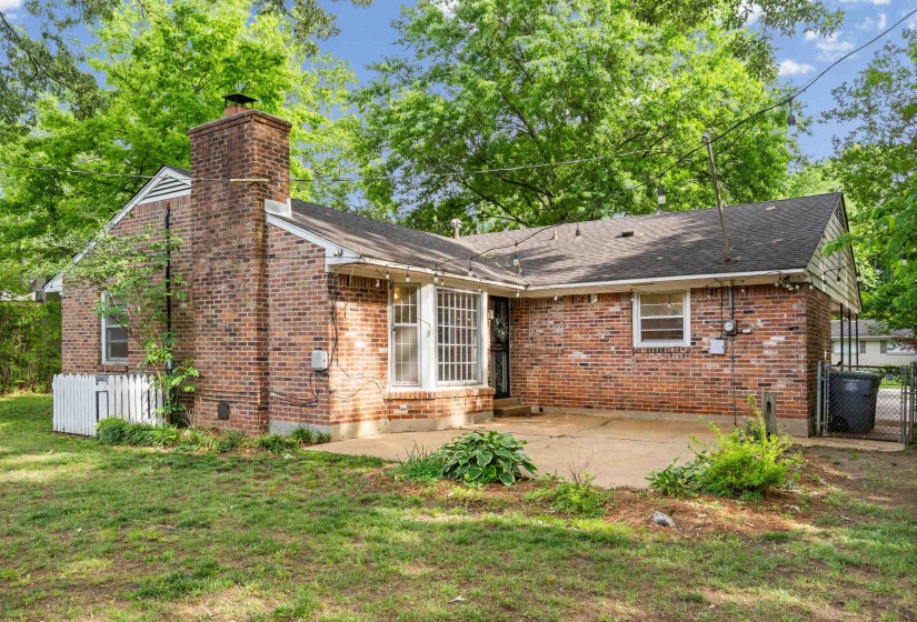 Brick-clad exterior featuring a prominent brick chimney, gabled roofline, and a concrete patio
