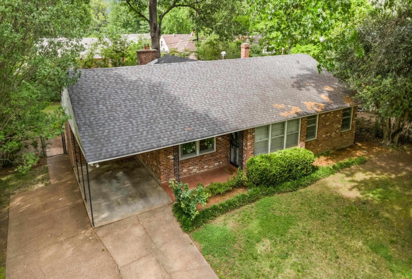 Brick exterior residence with a single-car carport, a paved driveway, and established landscaping