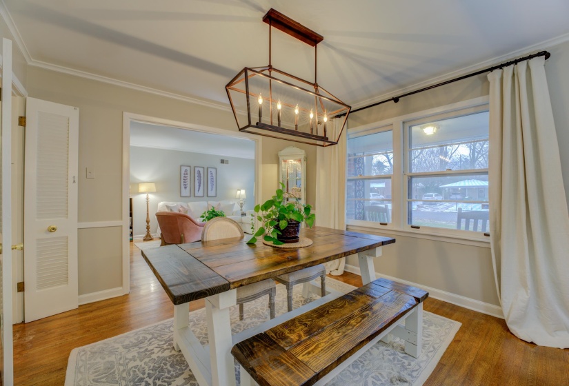 Dining area with wood-finish flooring, two large windows, a geometric ceiling light fixture, and crown molding