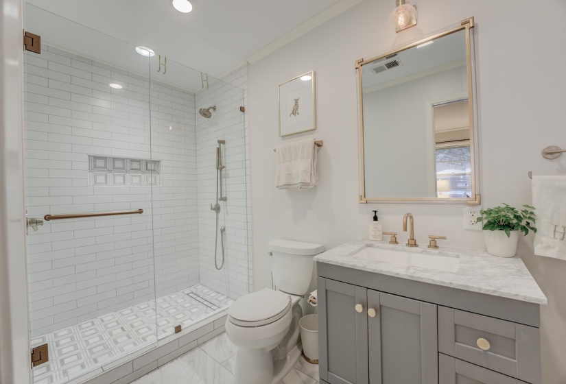 Glass-enclosed shower featuring subway tile surround, patterned floor tile, and a built-in shower niche