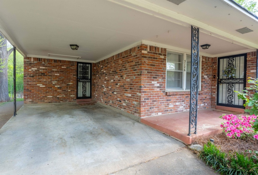 Brick exterior featuring a covered carport and a covered entry porch