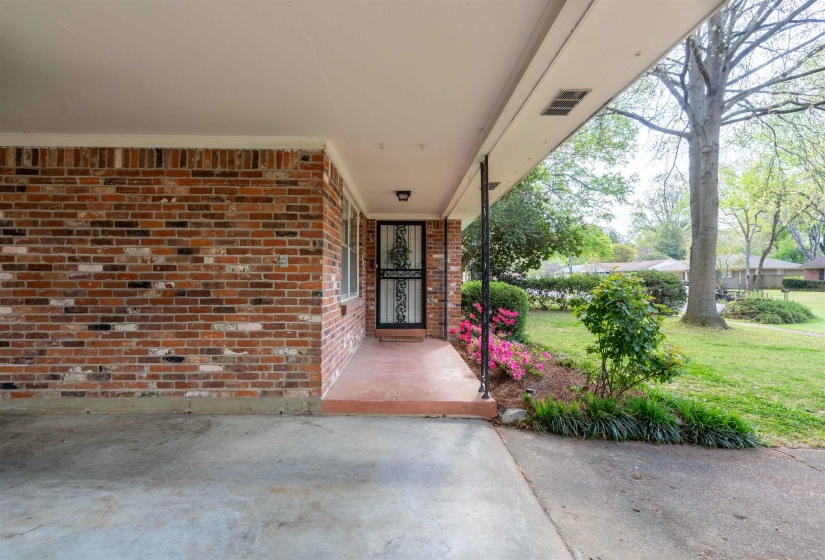 Brick exterior with a covered carport featuring a concrete floor